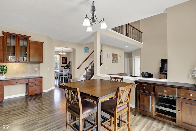 dining room with a chandelier, light wood-type flooring, stairs, and baseboards