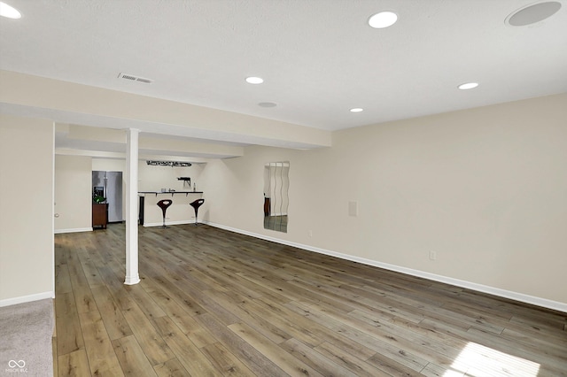 finished basement with baseboards, wood-type flooring, recessed lighting, and bar