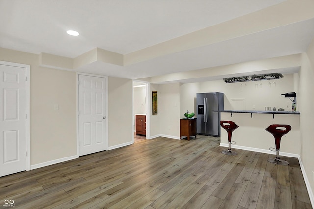 finished below grade area featuring stainless steel fridge, baseboards, wood-type flooring, and recessed lighting