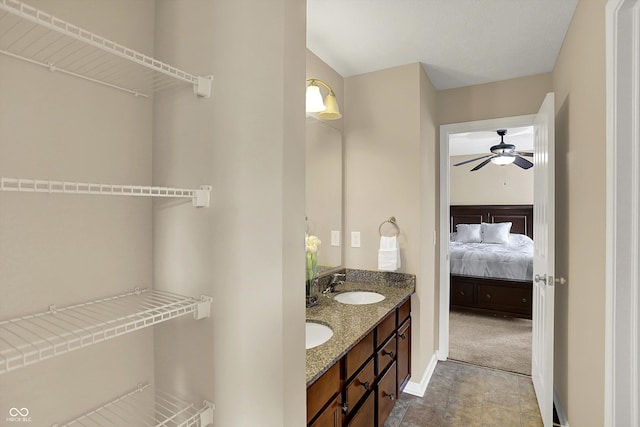 bathroom featuring ceiling fan, ensuite bathroom, baseboards, and double vanity