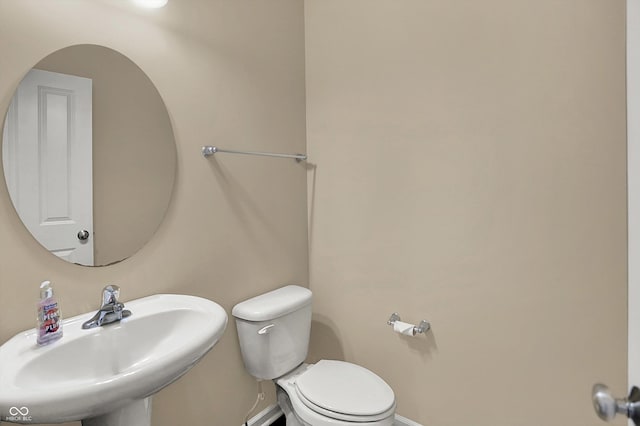 half bath with a sink, toilet, and baseboards