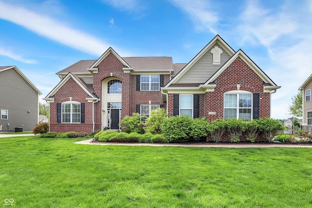 view of front of home with a front lawn, brick siding, and cooling unit