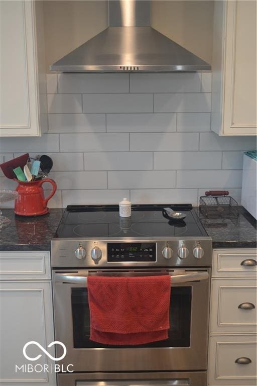 kitchen with white cabinets, decorative backsplash, wall chimney exhaust hood, and electric stove