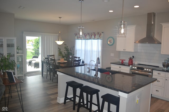 kitchen with wall chimney range hood, plenty of natural light, a sink, and stainless steel electric stove