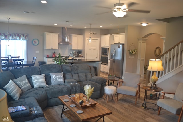 living area featuring recessed lighting, a ceiling fan, dark wood-style flooring, and arched walkways