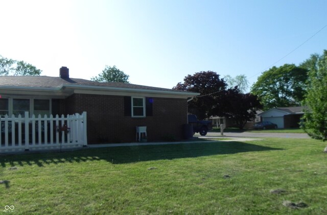 2630 Wedgewood Dr, Columbus, IN 47203 - view of side of home featuring a lawn, fence, a chimney, and brick siding