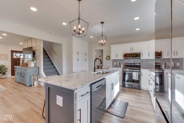 kitchen with decorative backsplash, a sink, a chandelier, stainless steel appliances, and recessed lighting
