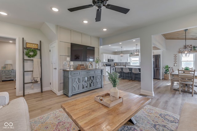 living area with recessed lighting, baseboards, ceiling fan with notable chandelier, and light wood-style floors