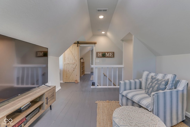 interior space featuring visible vents, lofted ceiling, hardwood / wood-style floors, baseboards, and an upstairs landing