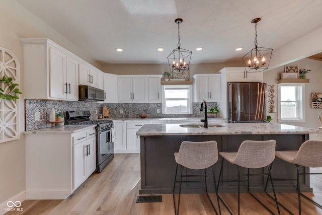 kitchen with an inviting chandelier, gas range oven, a sink, and freestanding refrigerator