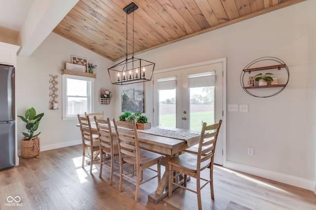dining room featuring lofted ceiling, light wood-style floors, baseboards, a chandelier, and french doors