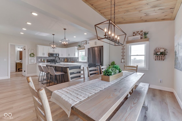 dining area featuring an inviting chandelier, baseboards, light wood-type flooring, and recessed lighting