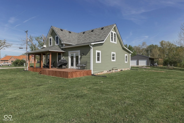 back of property featuring a garage, an outbuilding, a shingled roof, and a lawn