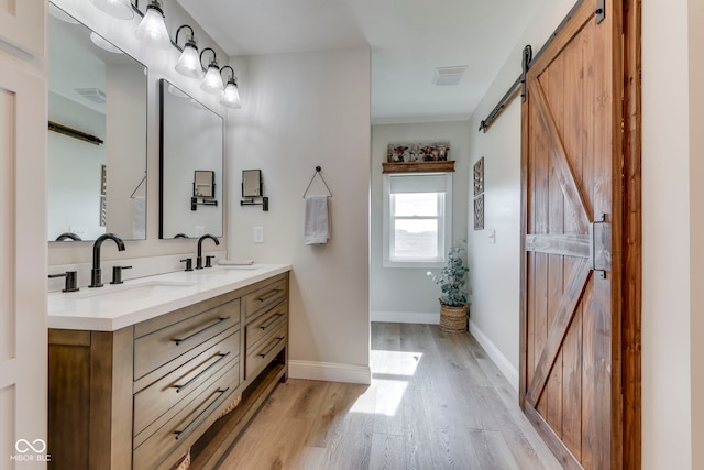 full bath with double vanity, a sink, wood finished floors, and visible vents