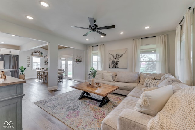 living area featuring baseboards, a ceiling fan, light wood-style flooring, and a wealth of natural light