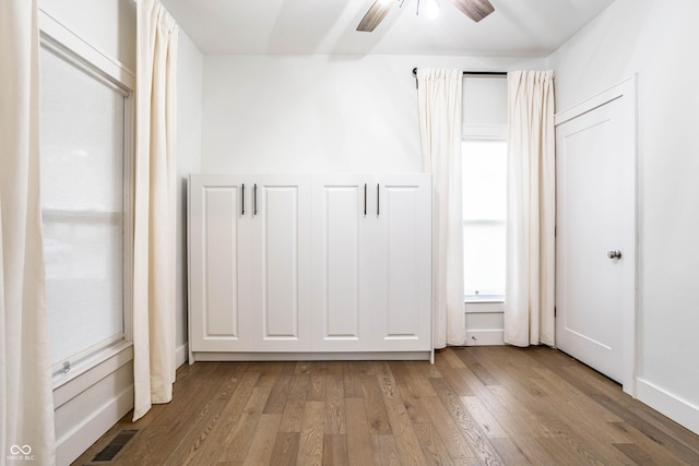 1451 N Grant Ave, Indianapolis, IN 46201 - unfurnished bedroom with wood finished floors, multiple windows, and ceiling fan
