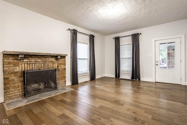 1451 N Grant Ave, Indianapolis, IN 46201 - unfurnished living room with wood finished floors, a textured ceiling, a fireplace, and baseboards