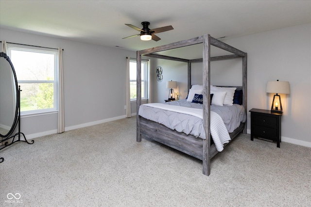 carpeted bedroom featuring a ceiling fan, baseboards, and multiple windows