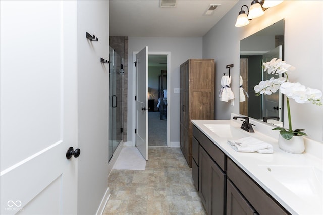 bathroom featuring double vanity, visible vents, a shower stall, a sink, and baseboards