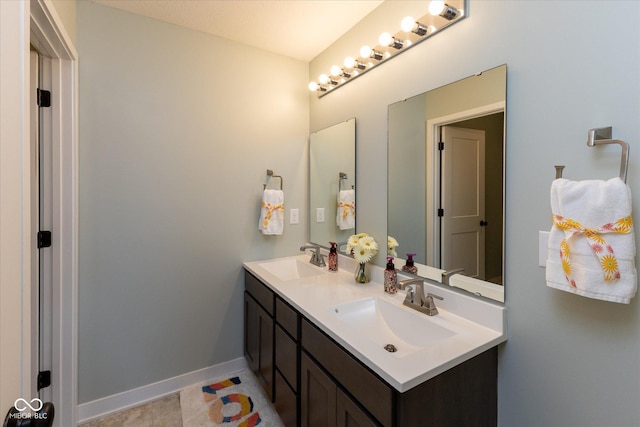 full bathroom with double vanity, baseboards, and a sink