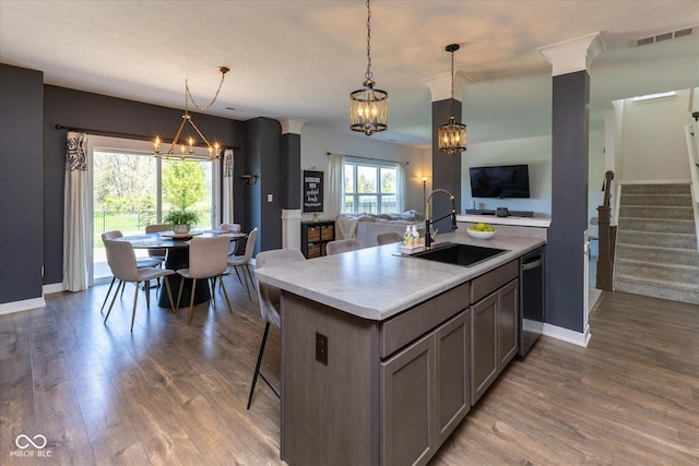 kitchen with a notable chandelier, a sink, open floor plan, wood finished floors, and stainless steel dishwasher