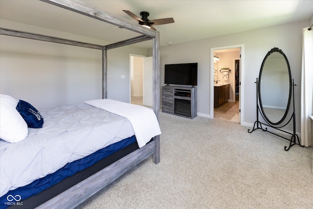 bedroom featuring baseboards, ceiling fan, light carpet, and connected bathroom