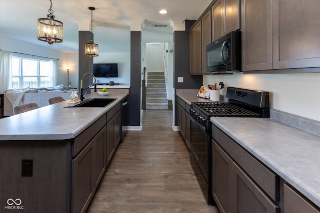 kitchen with pendant lighting, open floor plan, light countertops, a sink, and black appliances