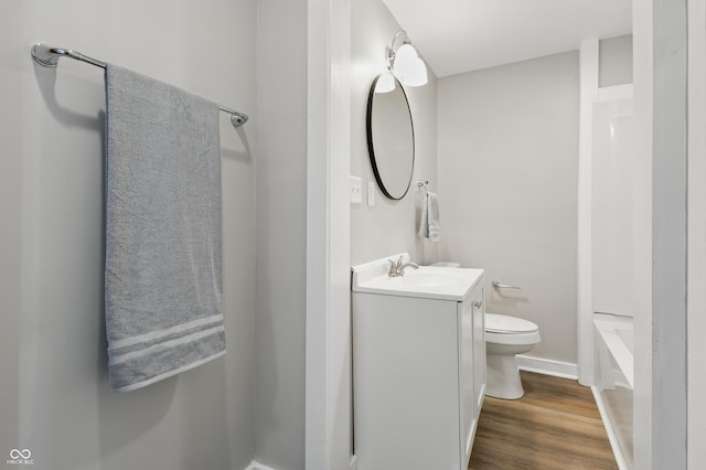 bathroom featuring vanity, wood finished floors, a shower, toilet, and baseboards