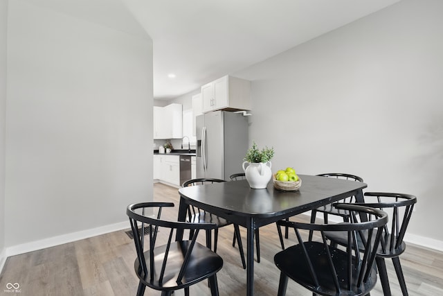 dining space featuring light wood-style floors and baseboards