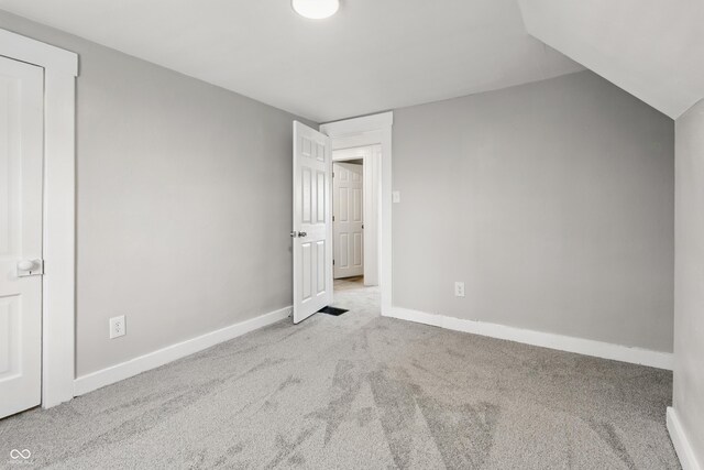 unfurnished bedroom featuring carpet floors, baseboards, and lofted ceiling