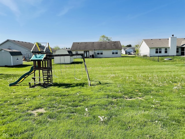 view of yard with an outdoor structure, a playground, fence, and a storage shed