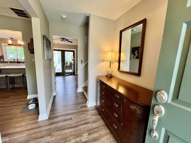 corridor with stairs, baseboards, visible vents, and wood finished floors