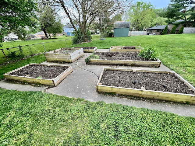 exterior space featuring fence, a storage unit, an outbuilding, a garden, and a yard