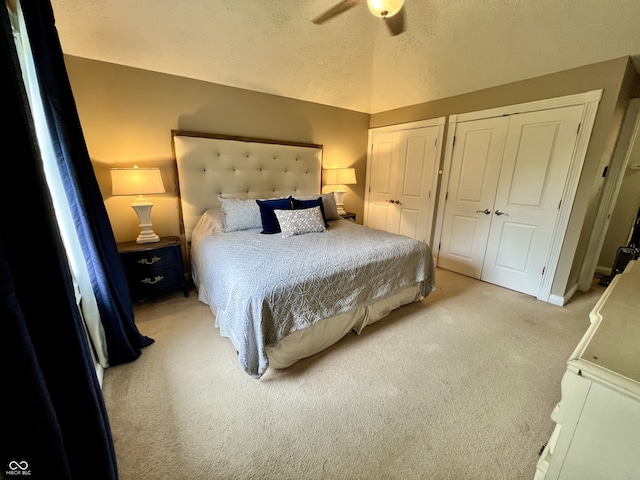 bedroom with a ceiling fan, multiple closets, light carpet, and vaulted ceiling