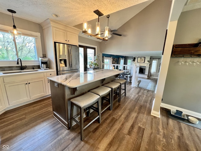 kitchen featuring a kitchen island, dark wood-style flooring, a textured ceiling, a sink, and stainless steel fridge with ice dispenser