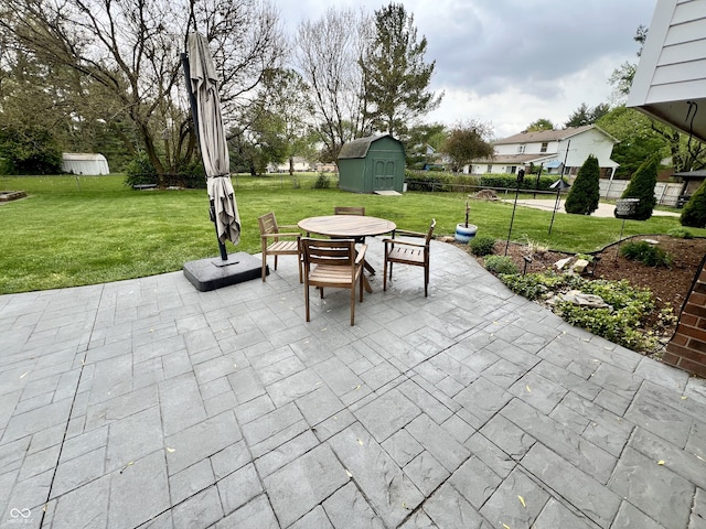 view of patio featuring outdoor dining area, a shed, an outbuilding, and fence