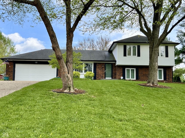split level home with an attached garage, driveway, a front lawn, and brick siding