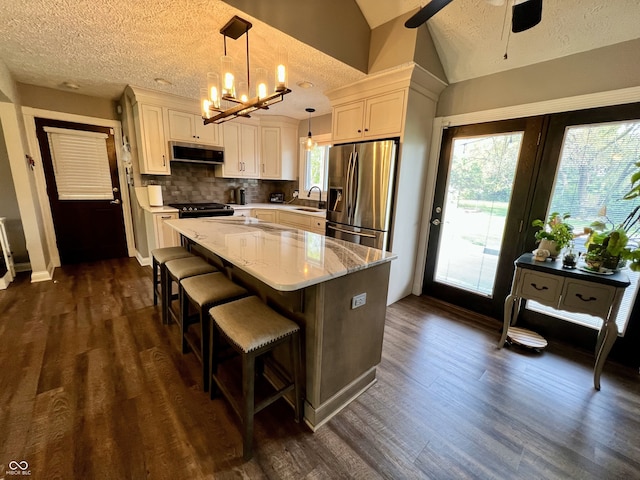 kitchen featuring lofted ceiling, ventilation hood, a sink, ceiling fan with notable chandelier, and stainless steel appliances