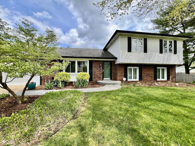 split level home featuring a garage, driveway, brick siding, and a front yard