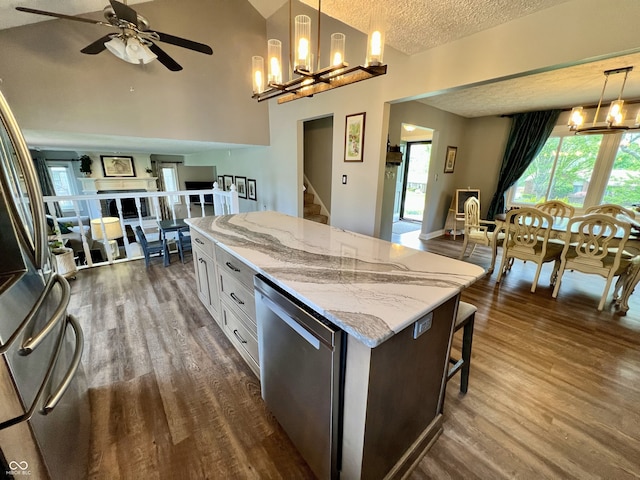 kitchen with ceiling fan with notable chandelier, stainless steel appliances, a textured ceiling, and dark wood-type flooring