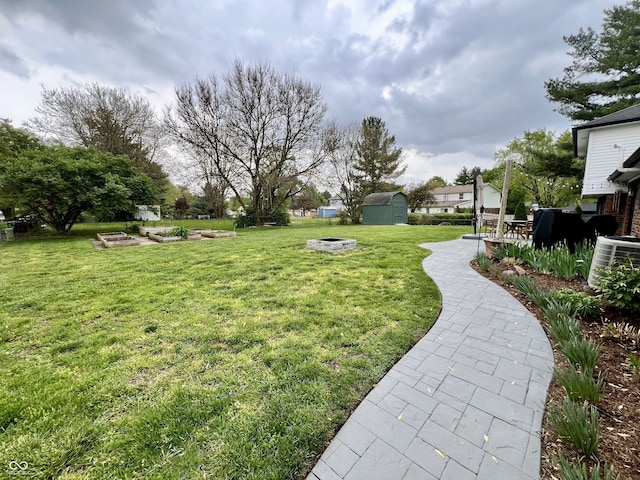 view of yard with an outdoor fire pit, an outbuilding, central AC unit, and a storage unit