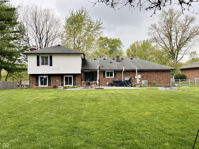 rear view of house featuring a yard, brick siding, a chimney, and a patio area