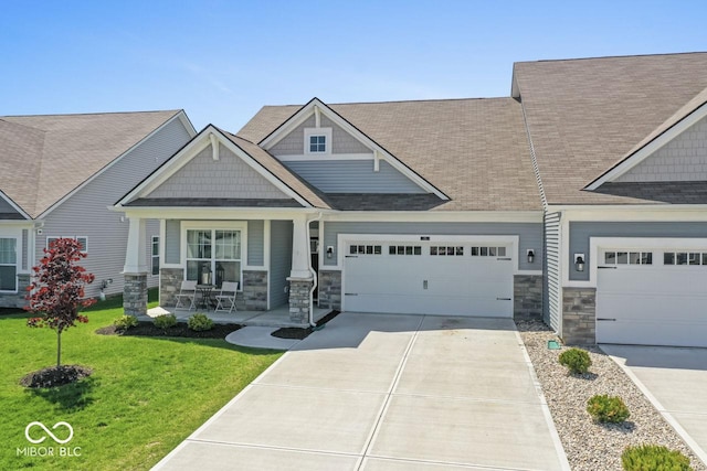 75 Hovden Dr, Cicero, IN 46034 - view of front facade featuring a shingled roof, a front lawn, stone siding, concrete driveway, and covered porch