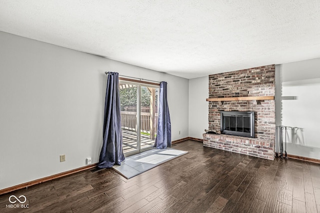 unfurnished living room featuring baseboards, a textured ceiling, wood finished floors, and a fireplace