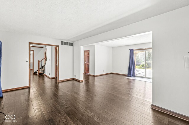 spare room featuring baseboards, visible vents, dark wood-style floors, and stairway