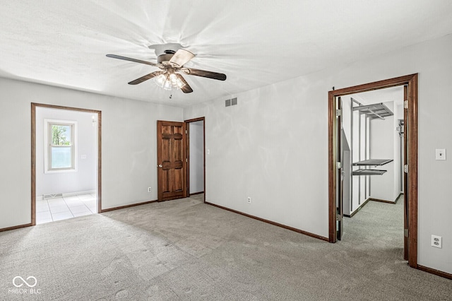 carpeted spare room featuring ceiling fan, visible vents, and baseboards