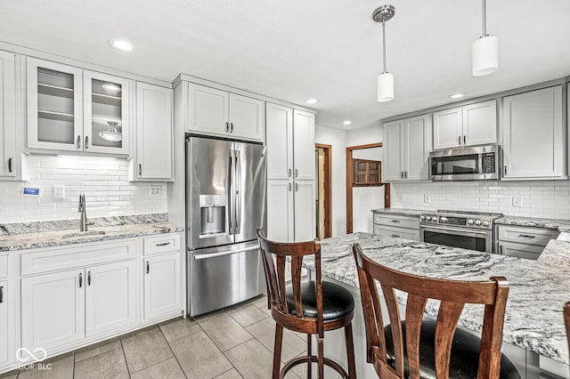 kitchen with decorative backsplash, pendant lighting, appliances with stainless steel finishes, and light stone countertops