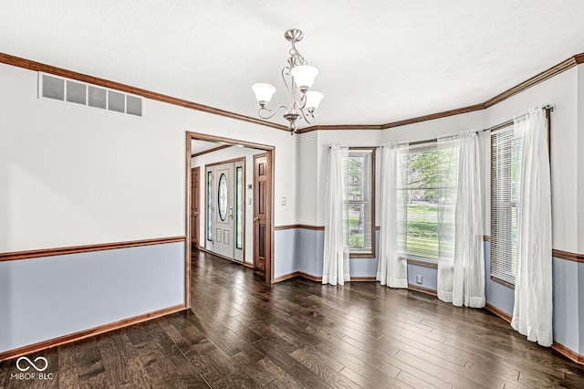 empty room featuring baseboards, a notable chandelier, wood finished floors, and visible vents