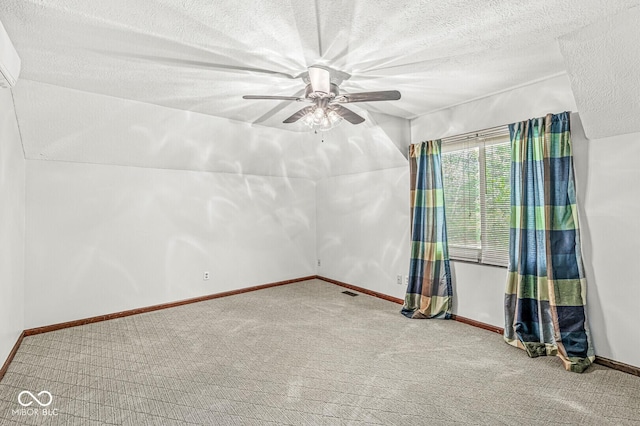 carpeted spare room with baseboards, a ceiling fan, a textured ceiling, and visible vents