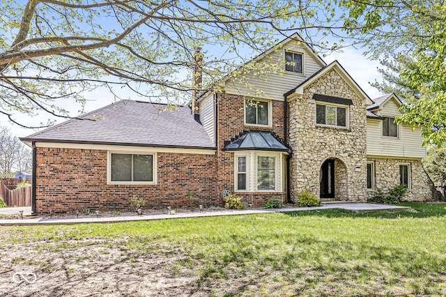 view of front facade featuring brick siding, a front lawn, and stone siding